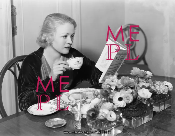 : Young woman sitting at the dining table holding : Young woman sitting at the dining table holding