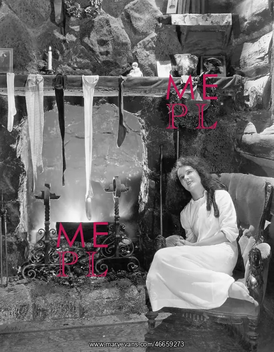 : Young woman sitting in front of a fireplace, drying : Young woman sitting in front of a fireplace, drying