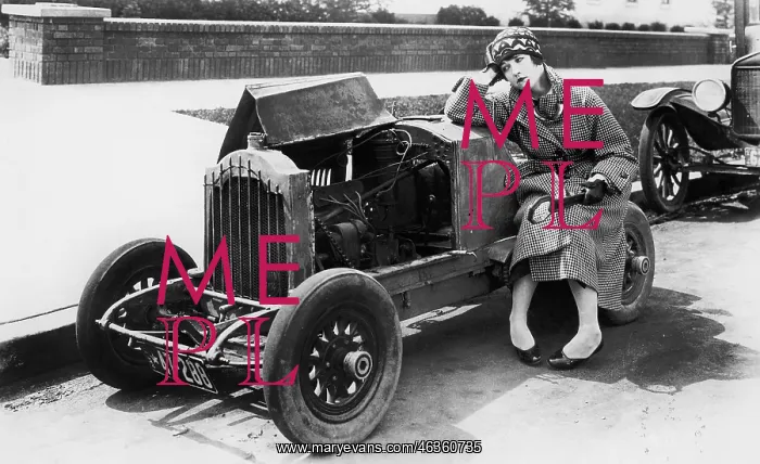 : Young woman sitting next to small car looking at : Young woman sitting next to small car looking at