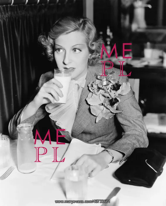 : Young woman sitting at a table in a restaurant drinking : Young woman sitting at a table in a restaurant drinking