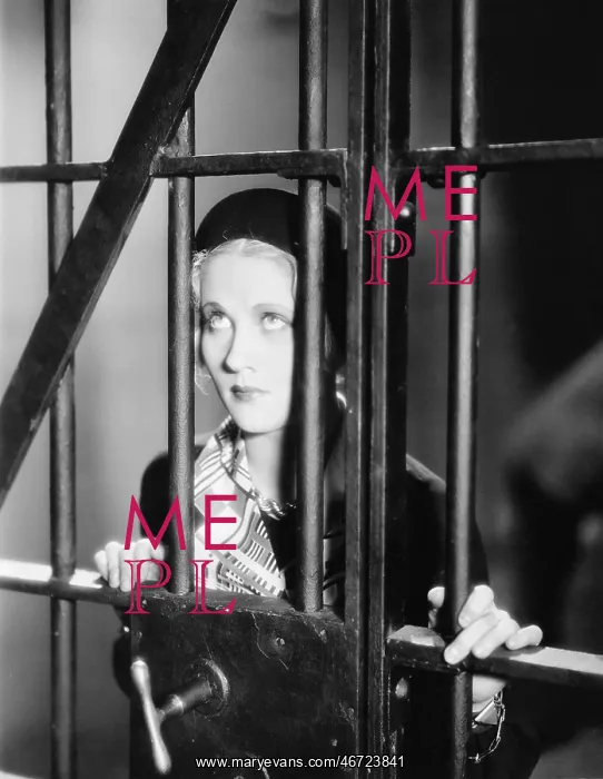 : Young woman standing behind bars in a prison cell : Young woman standing behind bars in a prison cell