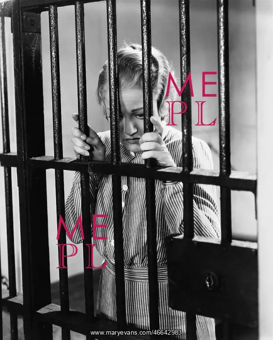 : Young woman standing in a prison cell : Young woman standing in a prison cell