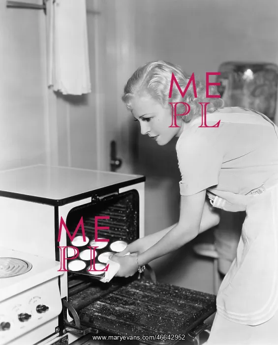 : Young woman taking cookies out of an oven : Young woman taking cookies out of an oven