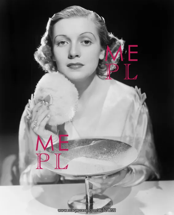 : Young woman using a powder puff : Young woman using a powder puff