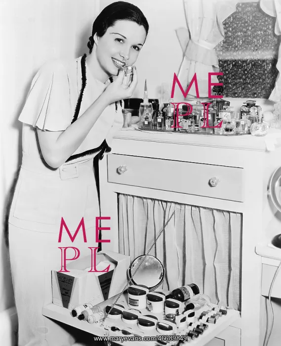 : Young woman at her vanity applying lipstick : Young woman at her vanity applying lipstick