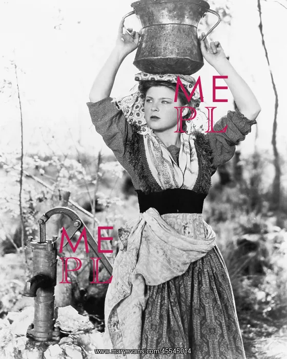 : Young woman with water bucket on her head next to a well : Young woman with water bucket on her head next to a well