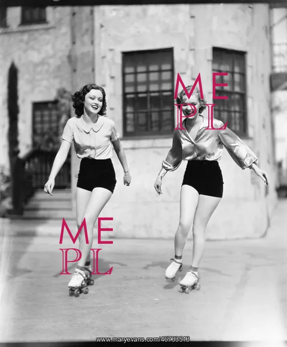 : Two young women roller skating on the road and smiling : Two young women roller skating on the road and smiling