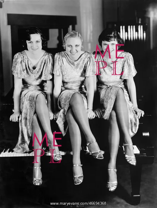 : Three young women sitting on top of a piano : Three young women sitting on top of a piano