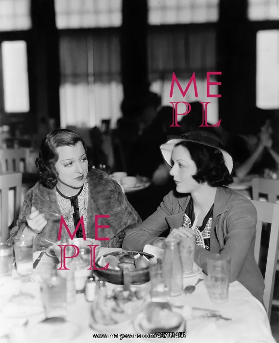 : Two young women sitting in a restaurant and looking : Two young women sitting in a restaurant and looking