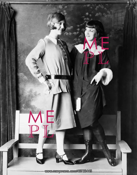 : Two young women standing on a bench smiling and : Two young women standing on a bench smiling and
