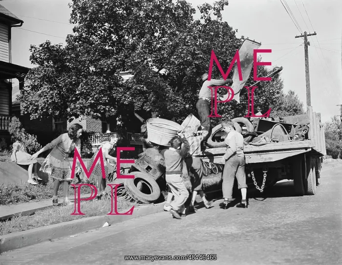 : Youngsters help load a truck with scrap metal : Youngsters help load a truck with scrap metal