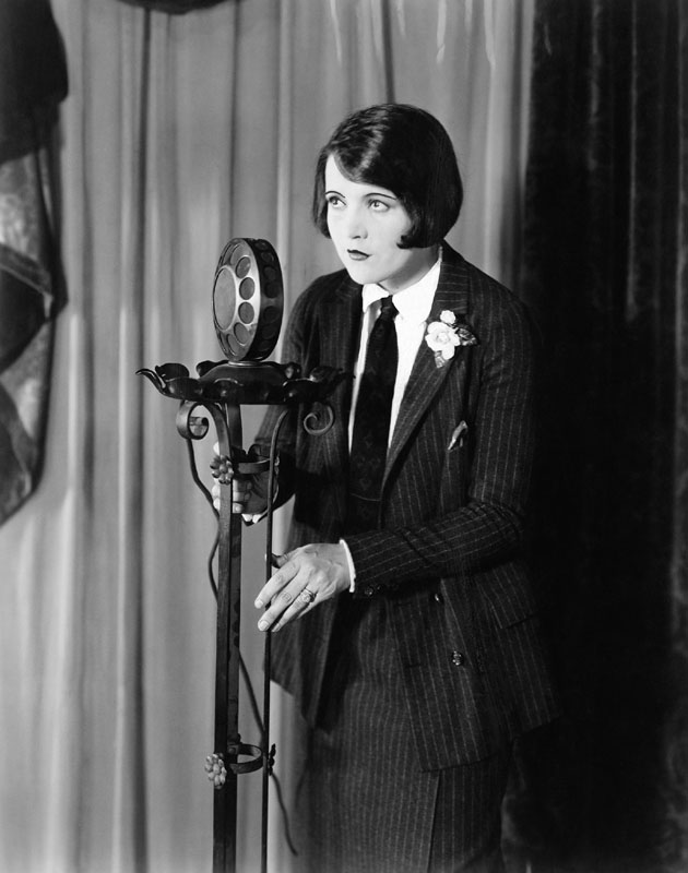 Woman in suit at microphone Date: