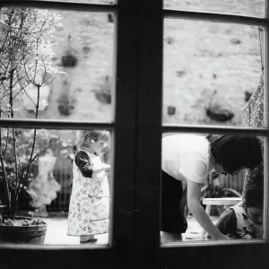 Three children in a garden, seen through the window Three children in a garden, seen through the window