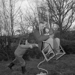 Family in a garden playing on a swing Family in a garden playing on a swing