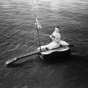 Man sitting on a guitar sailboat Man sitting on a guitar sailboat