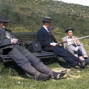 Three men on a bench in the countryside