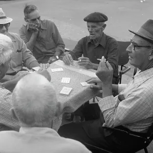 Six men playing cards at a table in the street Six men playing cards at a table in the street
