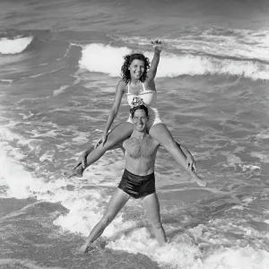 Smiling Couple Wearing Bathing Suits Playing in Surf Smiling Couple Wearing Bathing Suits Playing in Surf