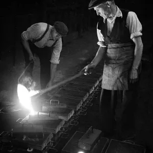 Workers in foundry pouring molten metal Workers in foundry pouring molten metal