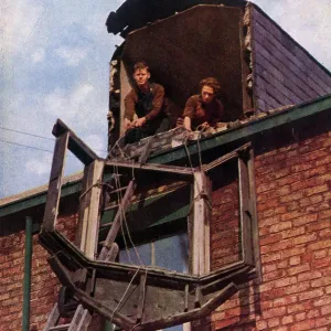 Two workers lowering a window pane Two workers lowering a window pane