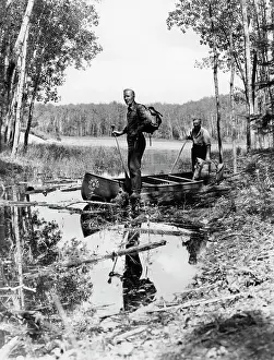 Backpacks: 1930s 1940s two men standing in canoe in shallow