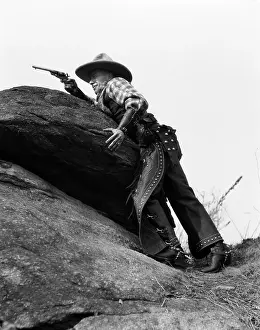 Gunslinger: 1930s Cowboy On Rocks Aiming Gun
