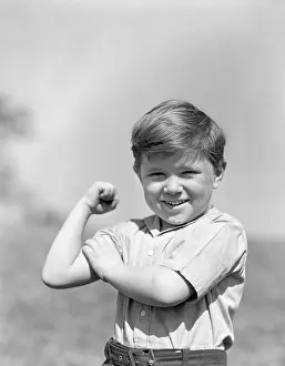 Flexing: 1930s Smiling Boy Making Strong Muscle Flexing Arm