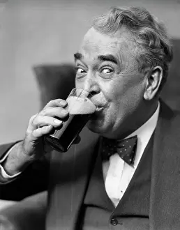 1930s SMILING EYES OF SENIOR MAN DRINKING BEER