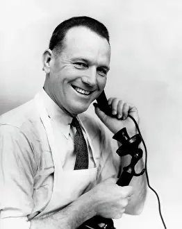 Phoning: 1930s SMILING GROCER IN APRON ON CANDLESTICK