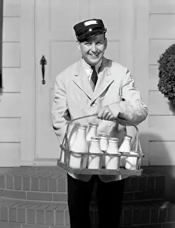 Pints: 1930s smiling milkman looking at camera delivering