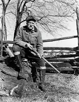 Gunning: 1940s elderly man sitting on wood split rail