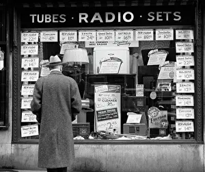 Merchandising: 1940s MAN LOOKING AT WINDOW DISPLAY OF RADIOS