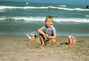 Kna001: 1950s 1954 LITTLE BOY PLAYING IN THE SAND AT