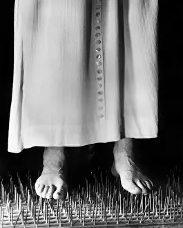 Ascetics: 1950s 1960s man walking barefoot on bed