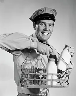 Milkmen: 1950s 1960s smiling milkman in uniform looking