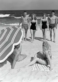 Sunbather: 1950s COUPLES IN BATHING SUITS WALKING TOWARDS