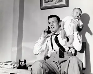 Sitter: 1950s Father Holding Baby While