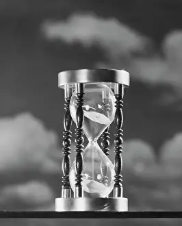 Sandglass: 1950s HOURGLASS AGAINST BACKGROUND OF CLOUDS