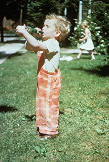 Kna001: 1950s LITTLE BOY OUTSIDE DRINKING SODA FROM A