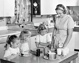 Peanut: 1950s Mother and Three Daughters Standing at Kitchen Table