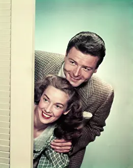 Nosy: 1950s SMILING COUPLE PEEKING AROUND CORNER OF