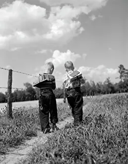 Crs001: 1950s BACK VIEW 2 BOYS WITH BOOK PACKS WALKING