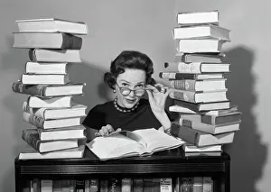 Quizzical: 1950s woman sitting between stacks of books pulling