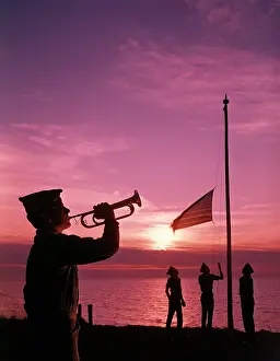 Reveille: 1960s BOY SCOUT BLOWING BUGLE AS OTHERS RAISE