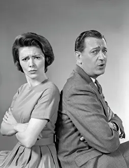 Grimacing: 1960s Couple Seated Back-To-Back