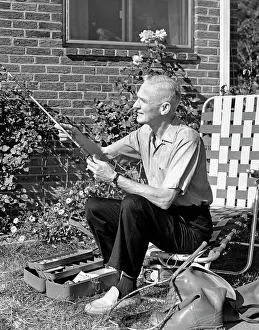 Fiddling: 1960s Elderly Man Seated On Lawn