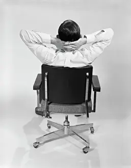 Faceless: 1960s MAN FROM BEHIND SITTING IN OFFICE EXECUTIVE