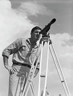 Theodolite: 1960s MAN USING A THEODOLITE WHILE SURVEYING