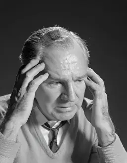 Sufferer: 1960s OLDER MAN WITH HANDS HOLDING HEAD TEMPLES