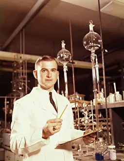 Beakers: 1960s SCIENTIST CONDUCTING A TITRATION EXPERIMENT